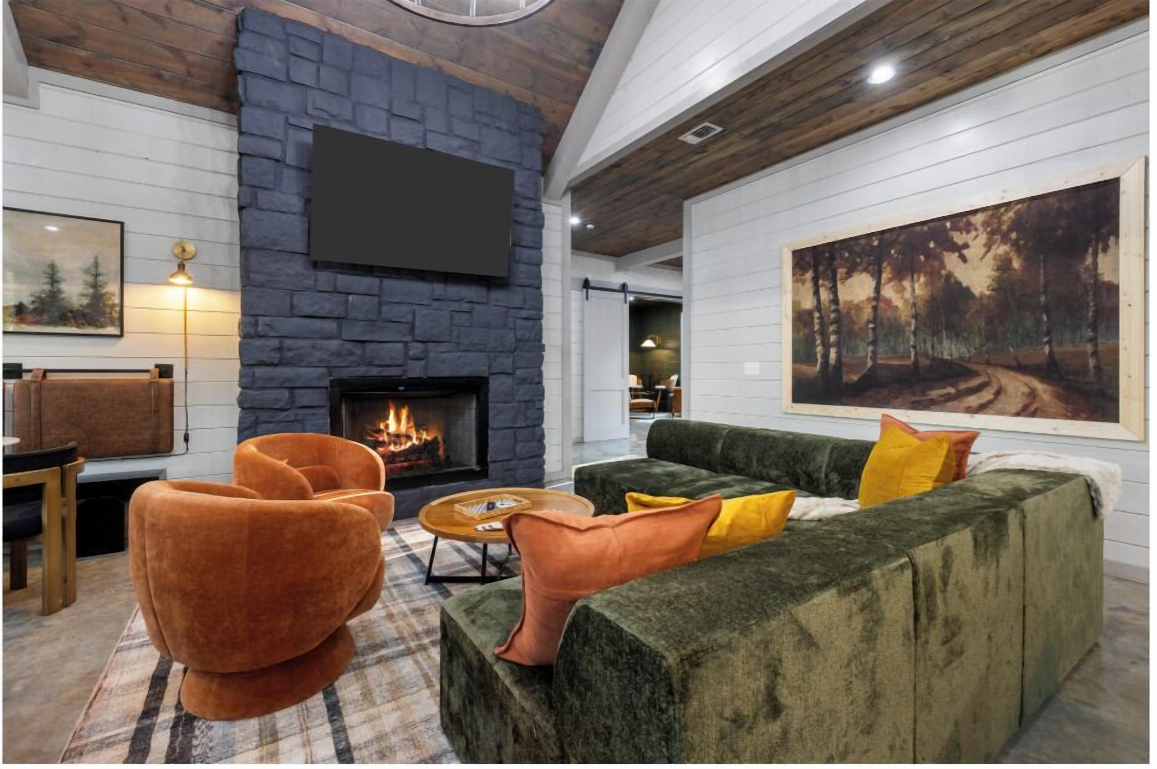A cozy living room with a fireplace, comfortable seating, and a large painting on the wall.