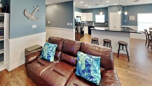 A brown leather sofa with floral cushions in a modern kitchen with wooden floors. - Fin & Feather | Spacious Port A Home, Steps to Sand (Port Aransas)