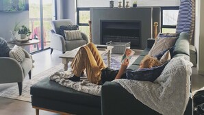 Una sala de estar moderna con chimenea, un sofá, una mesa de centro y una persona leyendo un libro.