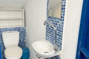 Et badeværelse med toilet, håndvask og blå fliser.