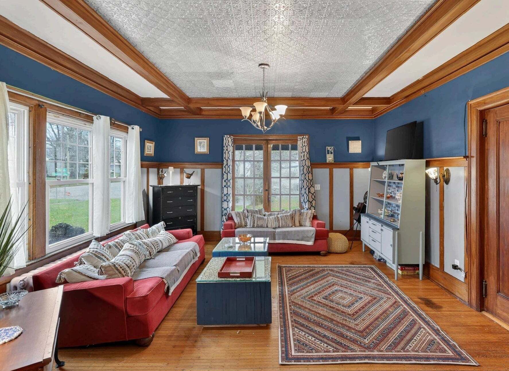 A living room with a red sofa, a coffee table, and a patterned rug.