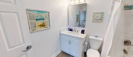 A bathroom with a toilet, sink, and shower curtain.