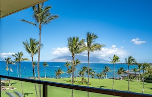 A view from a balcony overlooking a golf course with palm trees and a clear blue sky. - Kihei Surfside, #512 1 Bedroom Condo (Kihei)