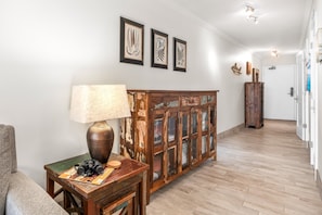 A hallway with a wooden cabinet, a lamp, and framed artwork on the wall. - Kihei Surfside, #512 1 Bedroom Condo (Kihei)