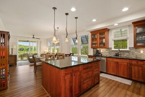 A modern kitchen with wooden cabinets, a large island, and pendant lighting. - Kauai Pili Mai 4k 3 Bedroom Condo (Koloa)