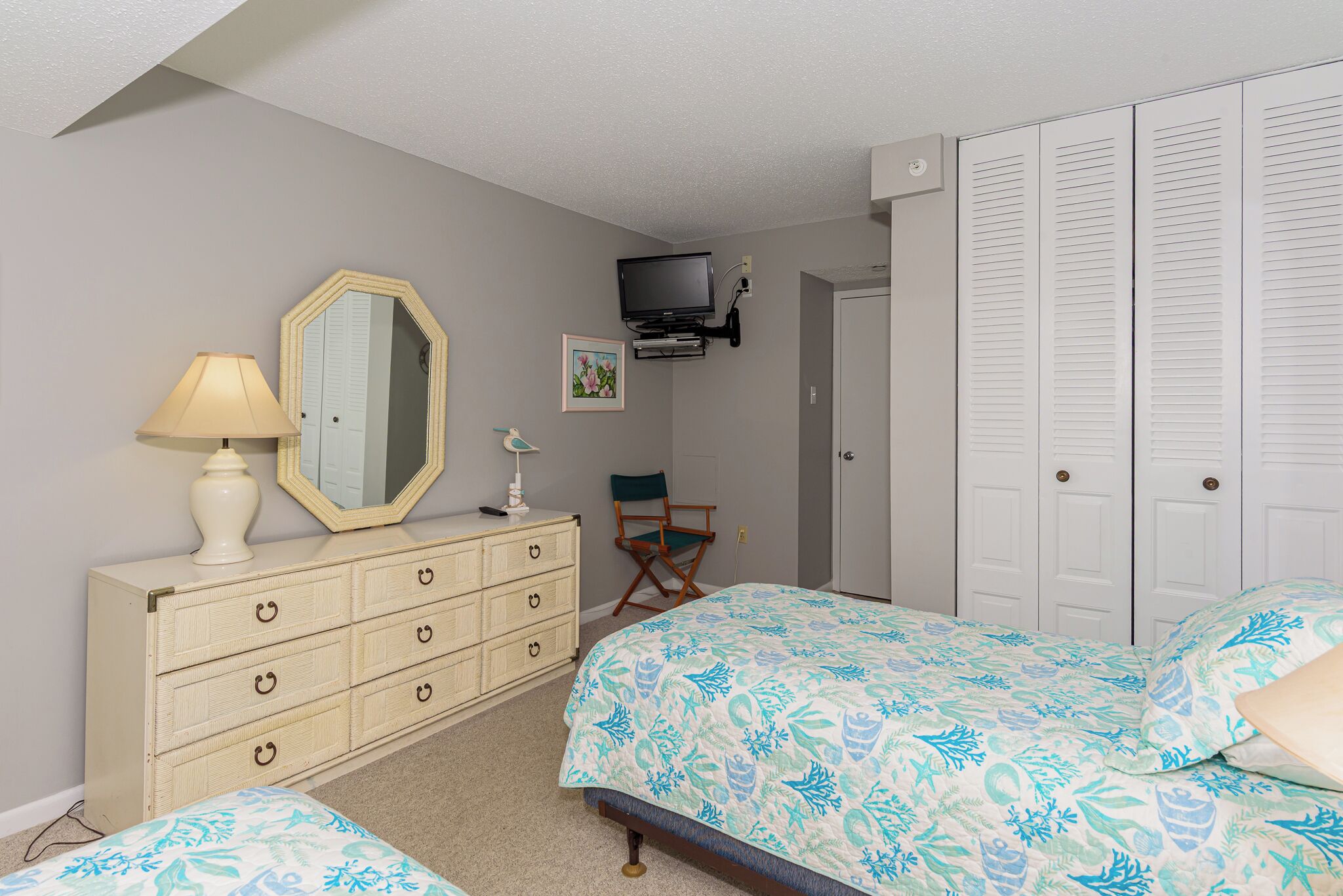 Un dormitorio con cama, cómoda, espejo, televisor y armario.