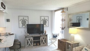 Un salon comprenant un téléviseur, une table à manger, un canapé et un fauteuil.