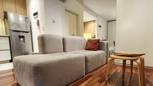 Uma sala de estar moderna com um sofá, uma mesa de centro de madeira e uma geladeira.