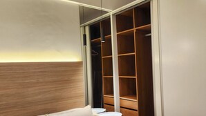 Quarto com cama, mesa de cabeceira, guarda-roupa e uma pequena mesa redonda.