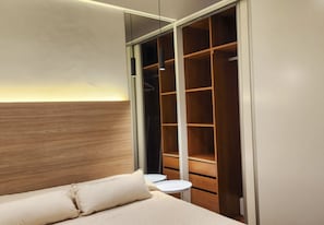 A bedroom with a bed, a bedside table, a wardrobe, and a small round table. - Palermo: Stylish Deco in a Functional Studio with Balcony (Buenos Aires)