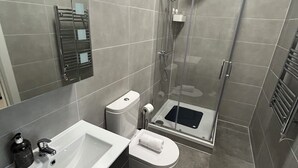 Une salle de bain moderne équipée d’un lavabo, de toilettes et d’une douche.