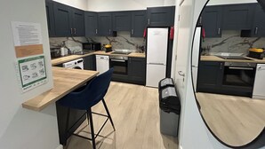 Une cuisine moderne avec des meubles de rangement de couleur sombre, un four à micro-ondes, un réfrigérateur et un évier.