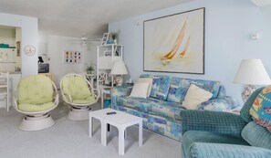 A living room with a sofa, chairs, a coffee table, a painting, and a clock. - Oceanfront Building With Great Ocean and Bay Views (Ocean City)