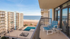 A balcony with a pool, chairs, and a view of the beach and ocean. - Oceanfront Building With Great Ocean and Bay Views (Ocean City)