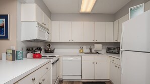 A kitchen with white cabinets, a microwave, a toaster, and a kettle. - Oceanfront Building With Great Ocean and Bay Views (Ocean City)