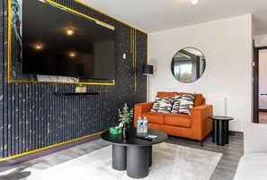 Un salon moderne avec un canapé, une table basse, un téléviseur et un miroir.