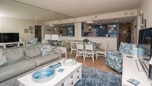 Una sala de estar moderna con un sofá gris, una mesa de centro blanca y un sillón azul estampado.