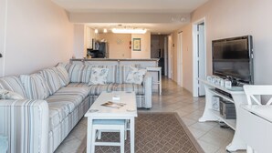 A living room with a sofa, a coffee table, a TV, and a kitchen in the background. - Ocean City's Premiere Building (Ocean City)