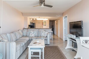 A living room with a sofa, a coffee table, a TV, and a kitchen in the background. - Ocean City's Premiere Building (Ocean City)