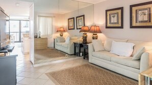A living room with a sofa, two side tables with lamps, a coffee table, a mirror, and framed pictures on the wall. - Ocean City's Premiere Building (Ocean City)