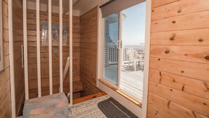 Ein Holzhütten-Innenraum mit Fenster, Tür und einem kleinen Tisch mit gemustertem Tischläufer.