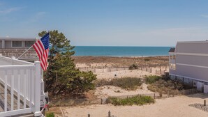 Blick auf einen Strand mit einem weißen Gebäude, einem Holzzaun und einer amerikanischen Flagge.
