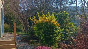 A garden with a wooden staircase leading to a building, surrounded by various plants and trees. - La Parenthèse enchantée (Le Vast)