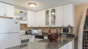 A kitchen with white cabinets, a granite countertop, a microwave, a toaster, a coffee maker, and a wine rack. - Oceanfront Building With Great Ocean and Bay Views (Ocean City)