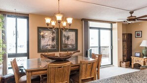 A dining area with a glass-top table, wooden chairs, a chandelier, and artwork on the walls. - Oceanfront Building With Great Ocean and Bay Views (Ocean City)