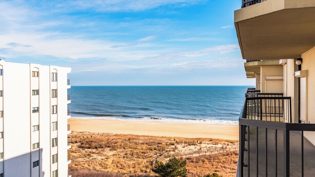 A beachfront view from a balcony overlooking a sandy beach and ocean. - Oceanfront Building With Great Ocean and Bay Views (Ocean City)