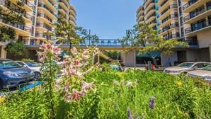 A hotel with multiple balconies, a central walkway, and parked cars. - Oceanfront Building With Great Ocean and Bay Views (Ocean City)