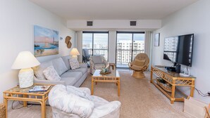 A living room with a sofa, armchair, coffee table, and television. - Oceanfront Building With Great Ocean and Bay Views (Ocean City)