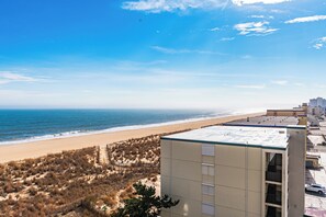 A coastal building with a flat roof, adjacent to a beach with sparse vegetation and a clear sky. - Oceanfront Building With Great Ocean and Bay Views (Ocean City)