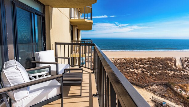 Een balkon met uitzicht op het strand, een stoel en een tafel.