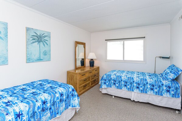 Un dormitorio con dos camas individuales, un aparador, un espejo y una ventana.