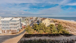 A coastal residential area with houses, a beach, and a clear sky.