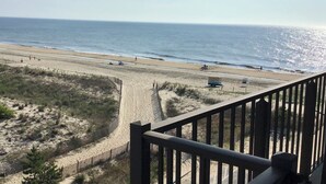 A beach view from a balcony with a railing, sandy beach, and ocean.