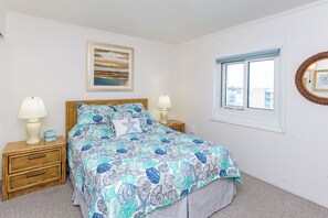 A bedroom with a bed, two bedside tables, a window, and a wall-mounted picture. - Great views from this oceanfront side view unit (Ocean City)