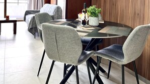 Un comedor moderno con una mesa redonda, sillas tapizadas de color gris y una planta en maceta.