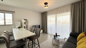 A modern living room with a dining area, a sofa, a TV, and a water dispenser. - 127 NIC - Stay Sun Line Apartment (Nicosia)