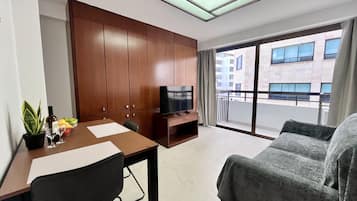 Uma sala de estar moderna com um armário de madeira, uma televisão de tela plana, uma mesa de jantar com cadeiras, um sofá e uma varanda com vista para a cidade.
