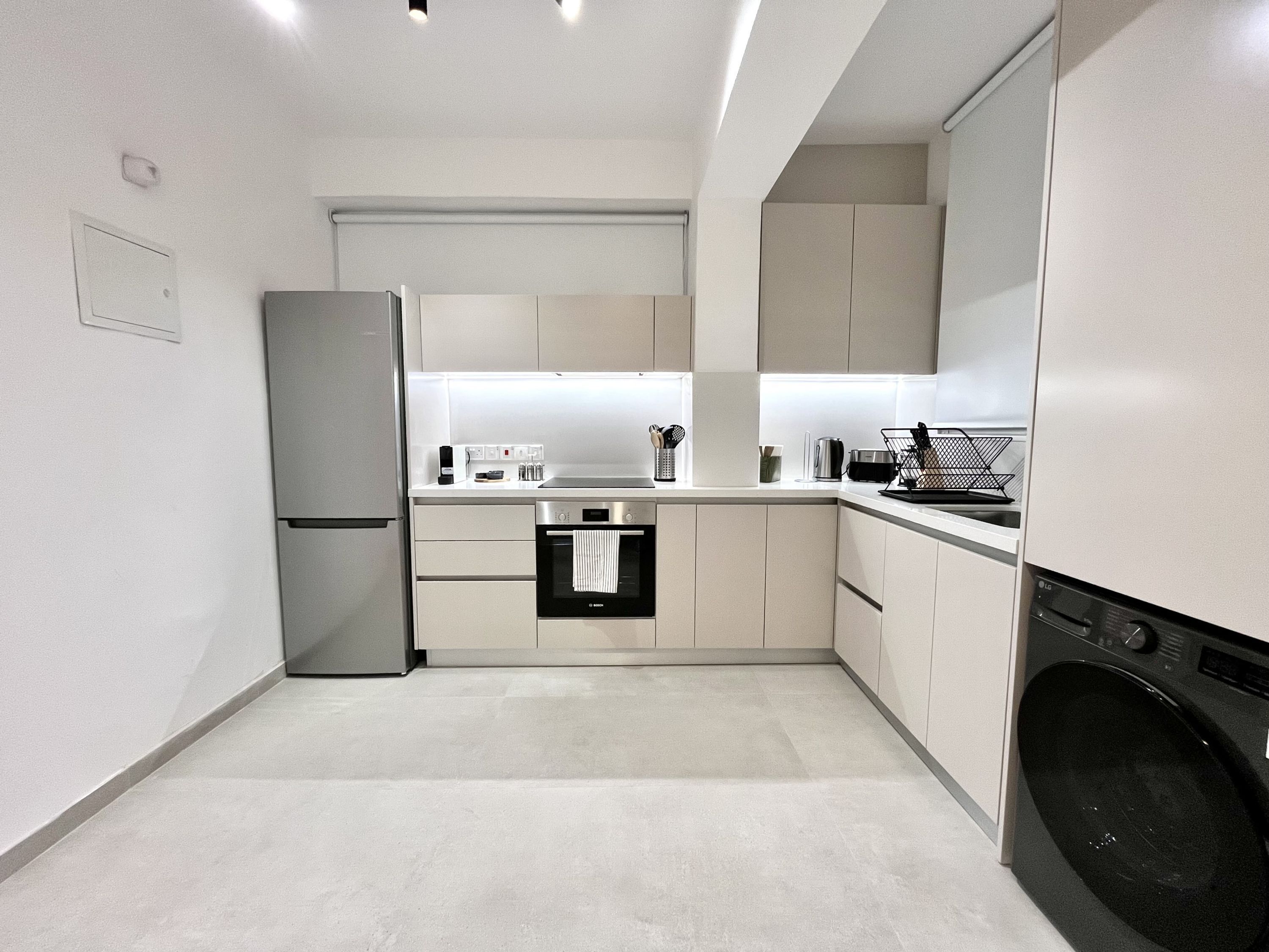 A modern kitchen with a built-in oven, a washing machine, and a refrigerator.
