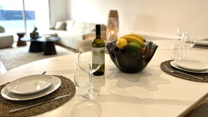 Una mesa de comedor con un cuenco de fruta, una botella de vino y copas de vino.