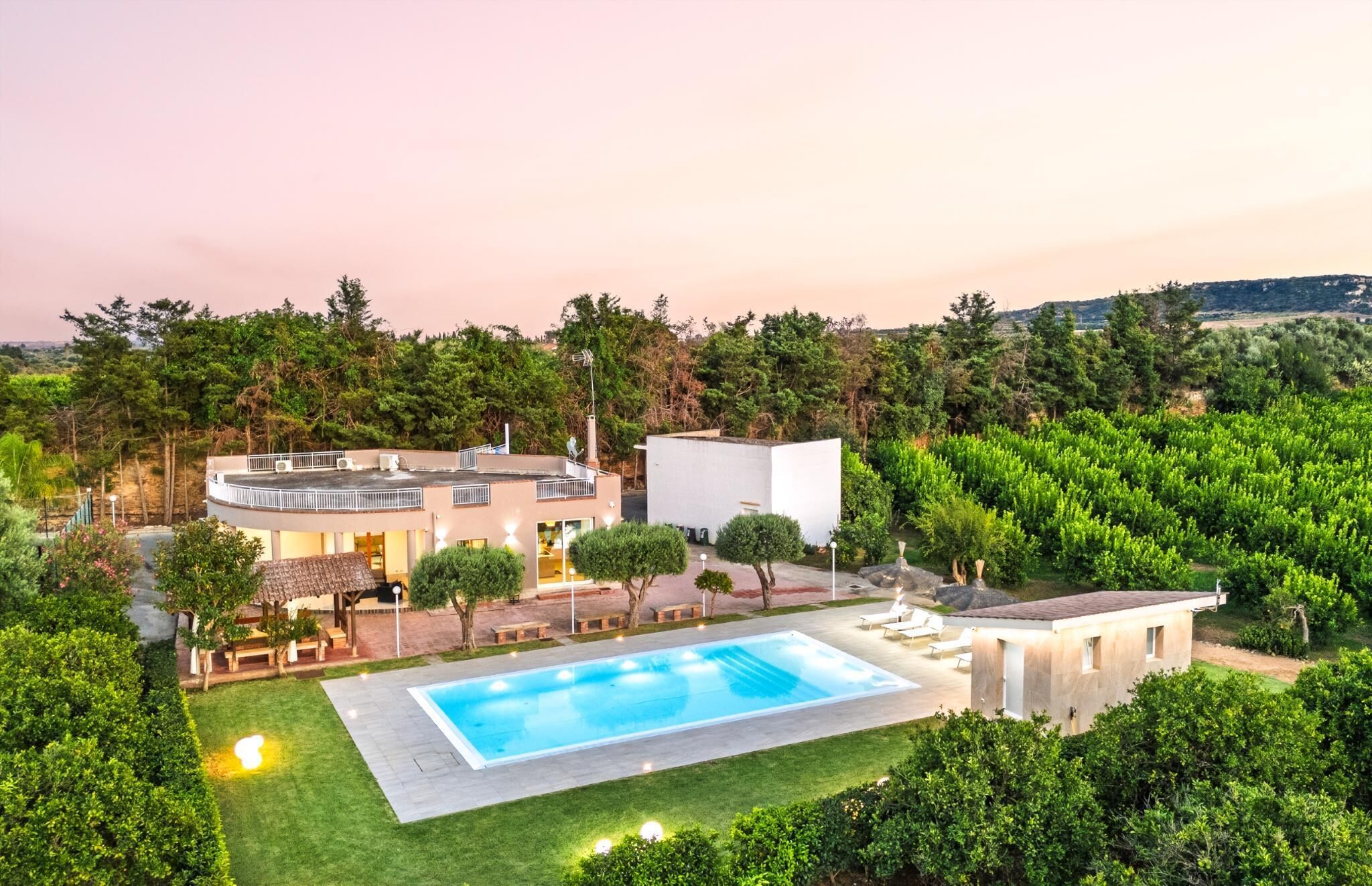 Une villa moderne dotée d’une piscine, entourée d’une végétation luxuriante et située dans un paysage vallonné.