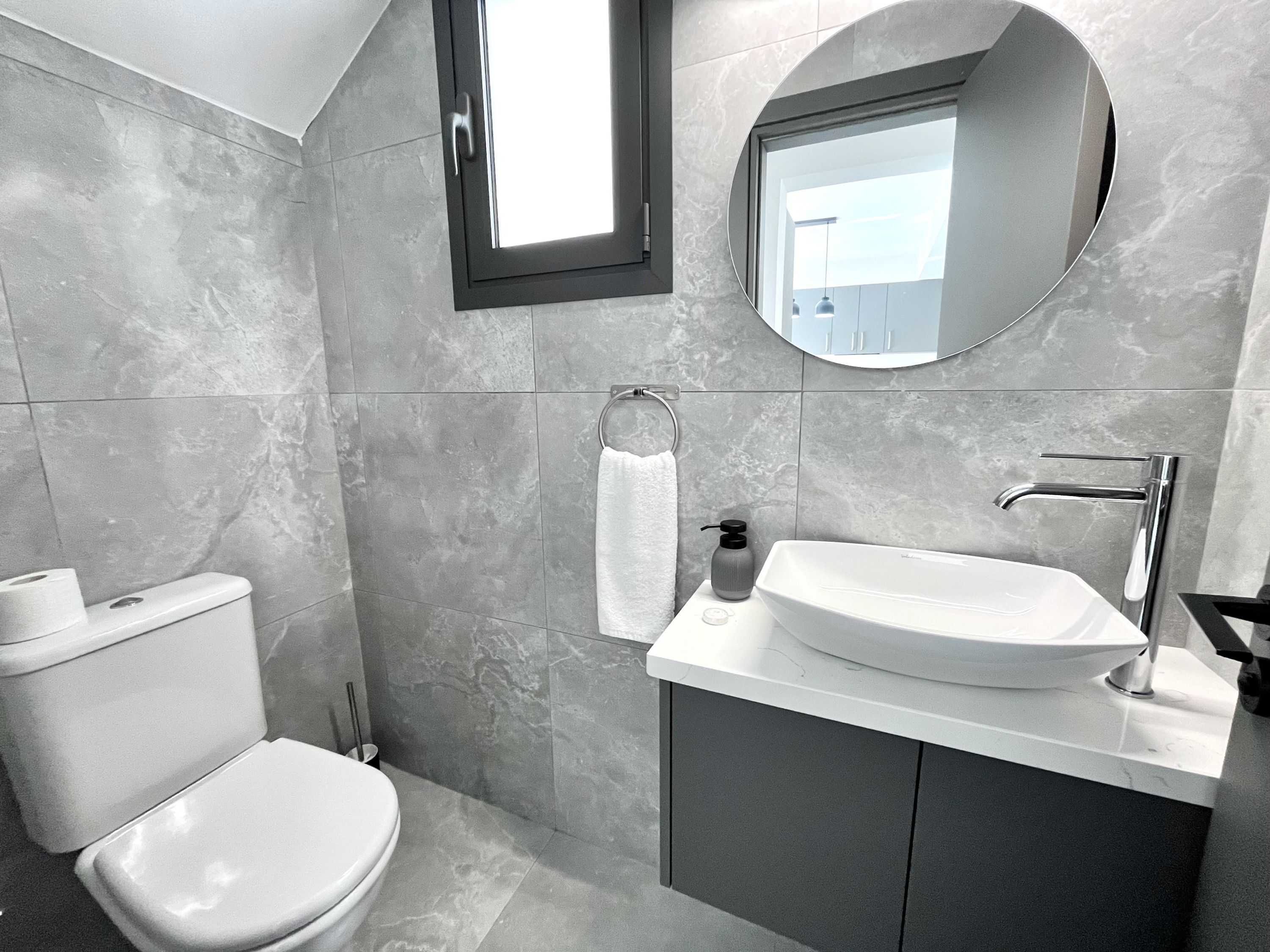 A modern bathroom with a toilet, sink, and mirror.