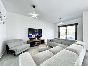 Ein modernes Wohnzimmer mit einer Eckcouch, einem Flachbildfernseher und einer Holzunterhaltungseinheit.