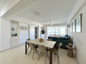 Ein geräumiger Wohnbereich mit Esstisch, Stühlen, einer Couch und einem Fernseher.