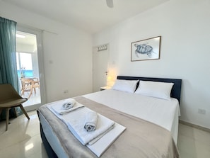 Ein Hotelzimmer mit Bett, Sessel, Tisch und Meerblick.