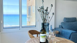 A room with a wooden table, a bottle of wine, and a glass. There is a window with a view of the sea. - 39 LCA - Stay Makenzie View Apartment (Larnaca)