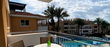 En balkon med et rundt bord, stole og en flaske.